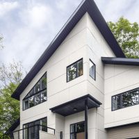 A modern home with white siding and black trim around the roof and windows.