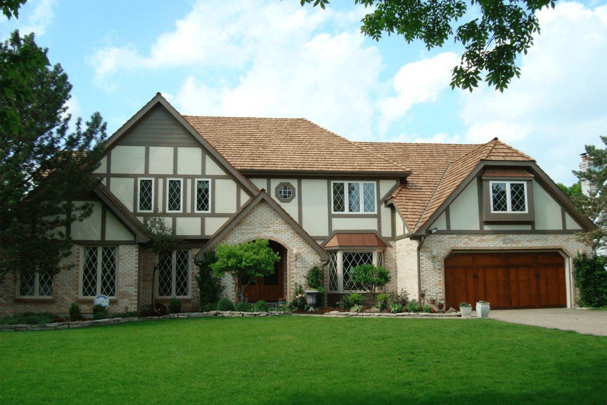 A 2 story home with ivory siding, brown vertical accent siding, and brick along the first story.