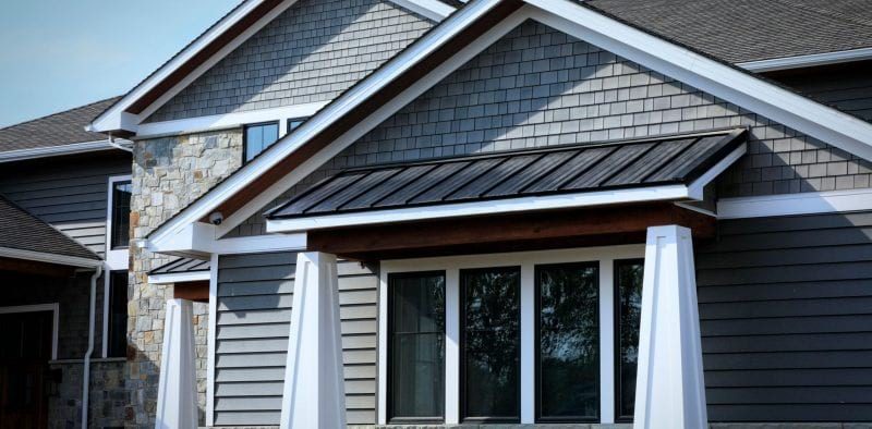 A home with gray clapboard and Beach House Shake siding, stone accenting, and white trim.