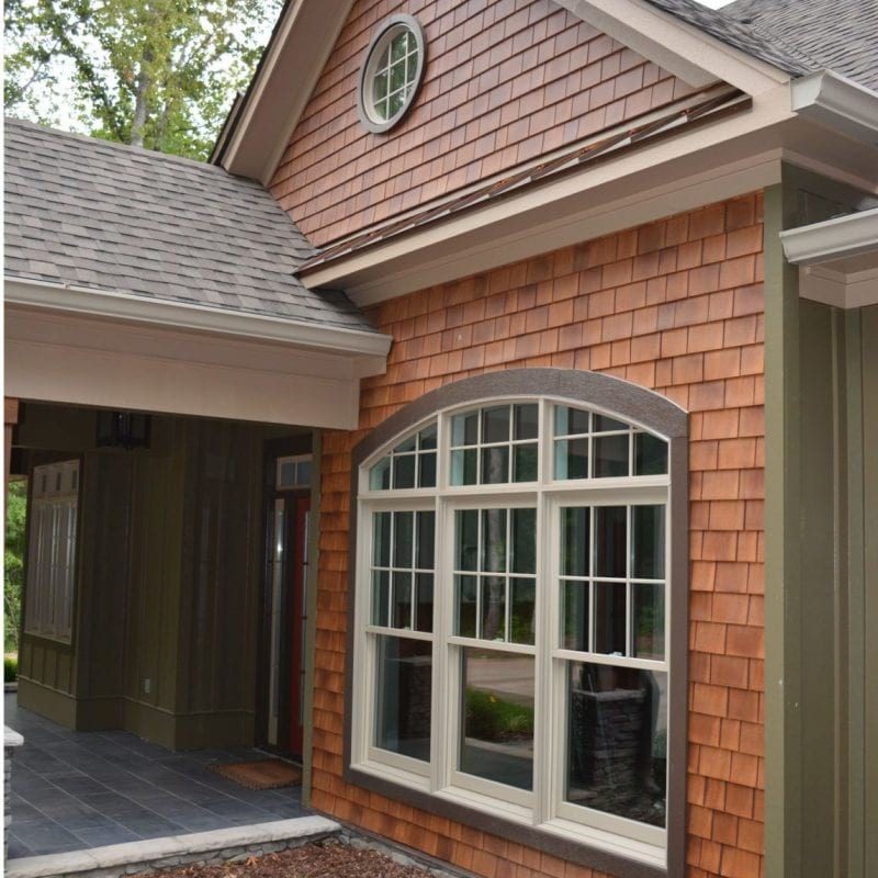 The entry way of a home with cedar Beach House Shake siding and green trim.