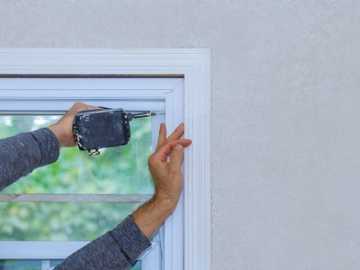 A construction worker installing a window in a new house using a drill.