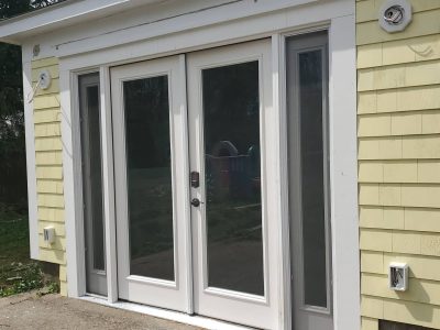 White hinged patio doors on a yellow home.