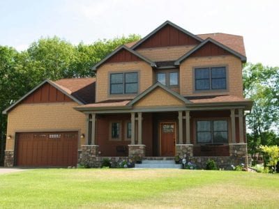 A large 2 story home with tan shake and mahogany board and batten JamesHardie siding.