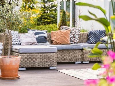 A wood deck with a wicker couch and several potted plants.