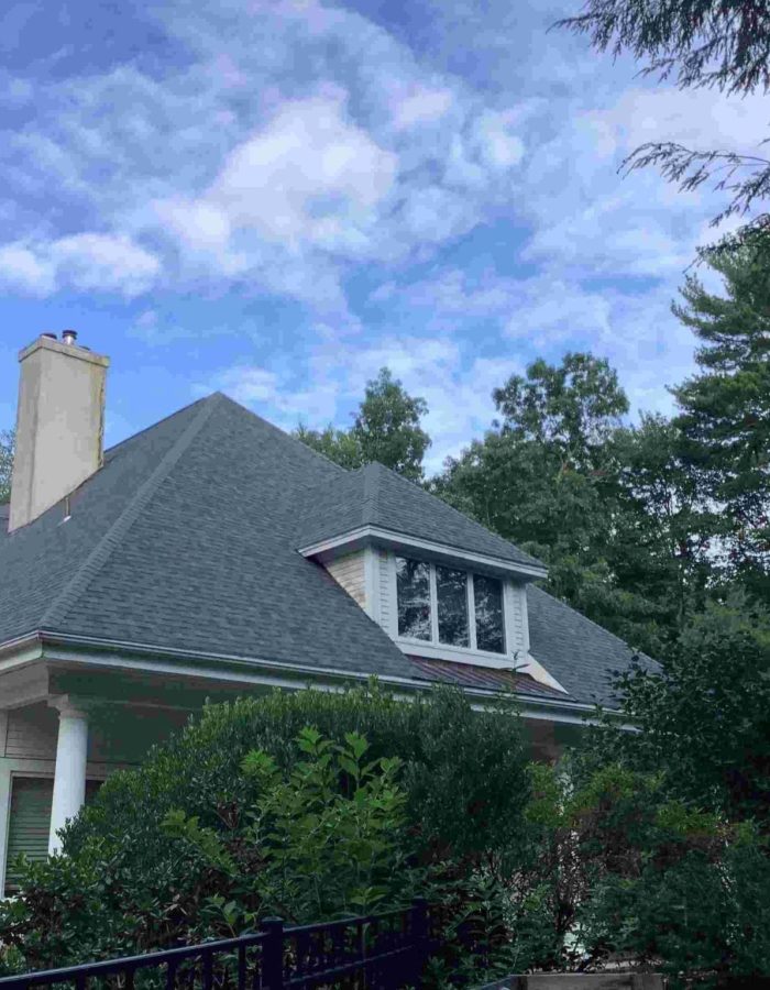 A home with gray asphalt shingle roofing and a single cement chimney.